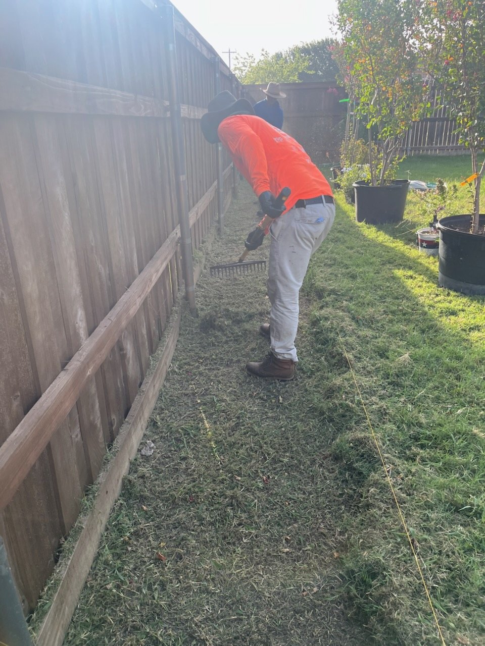 Worker raking the edge of a planting bed