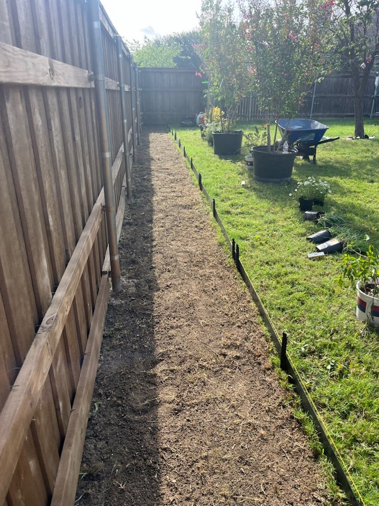 Prepared planting bed along a wooden fence
