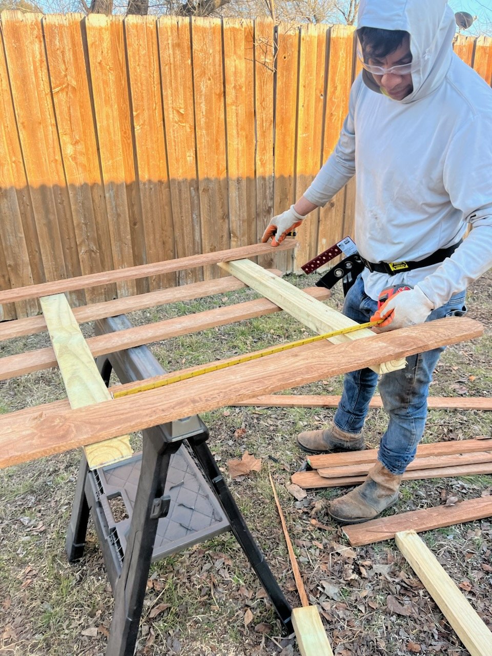 Worker measuring boards for a fence panel