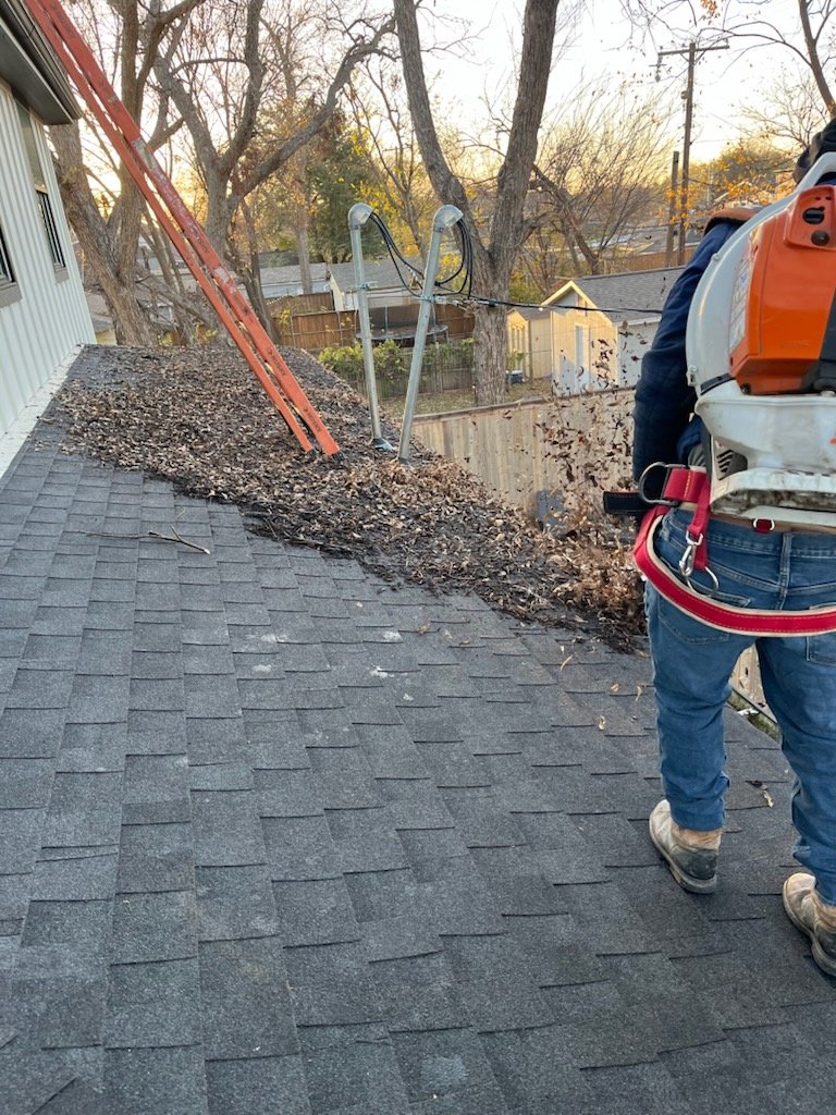 Worker clearing leaves from a roof